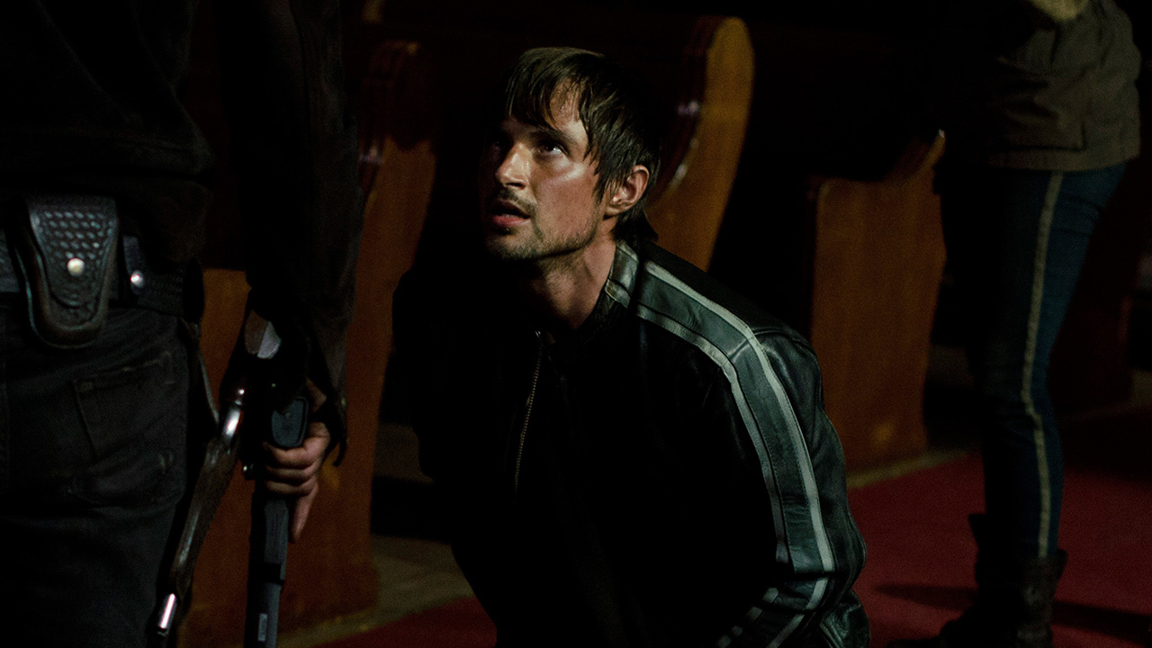 Gareth on his knees in a church, looking up in a scene from The Walking Dead.