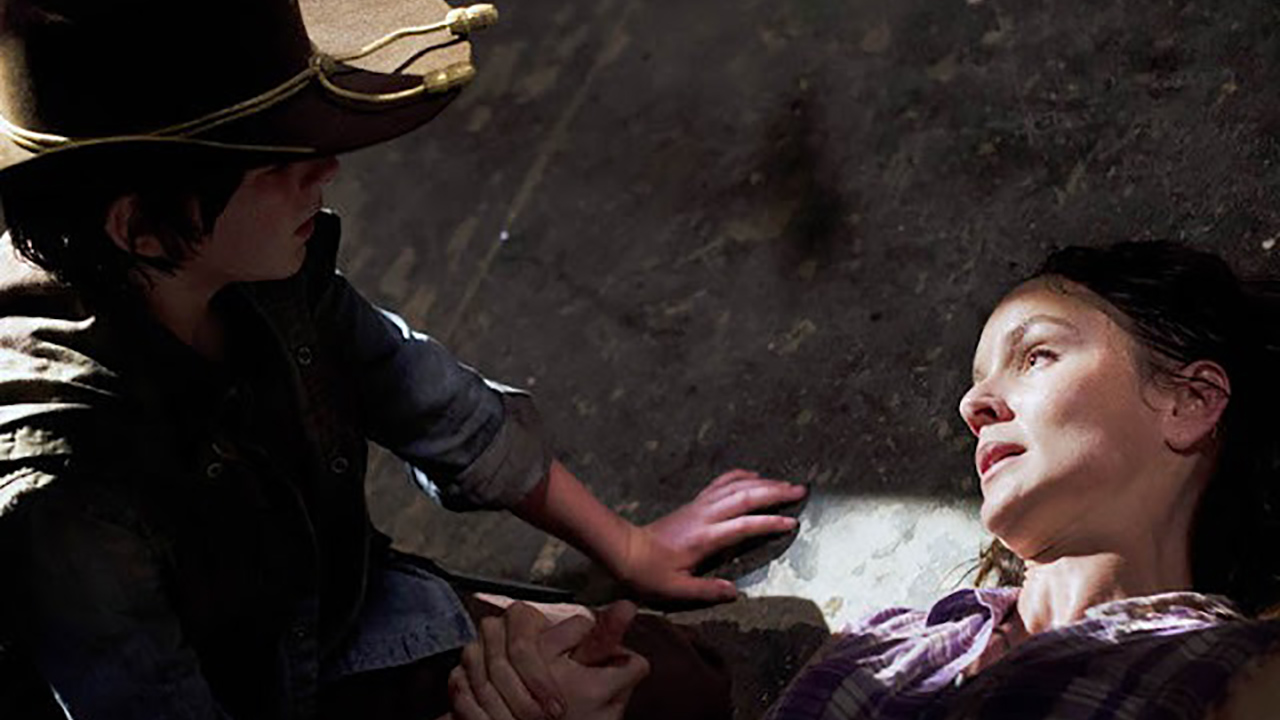 Lori lying on the ground, Carl standing over her in a scene from The Walking Dead.