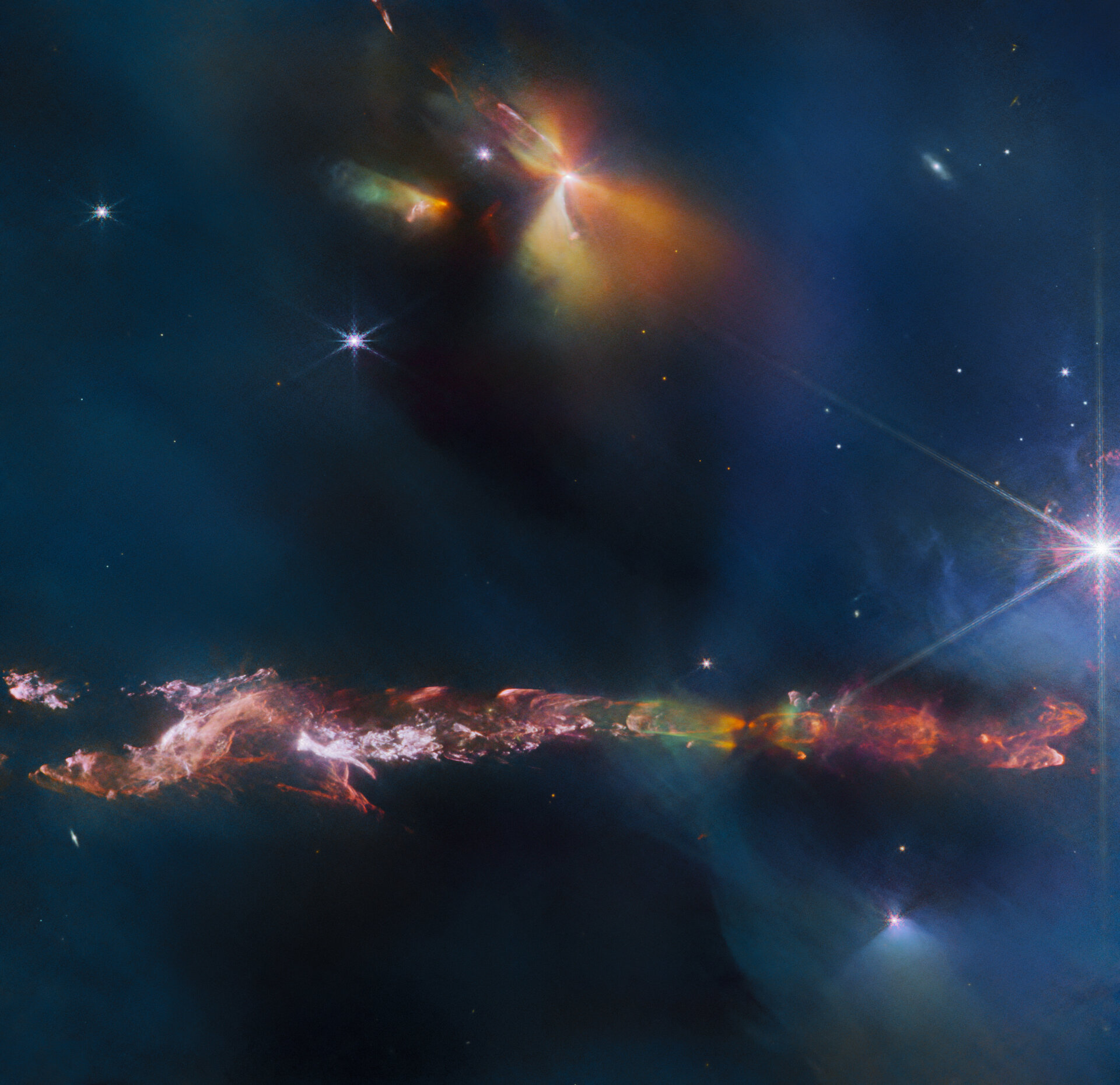 The NASA/ESA/CSA James Webb Space Telescope reveals intricate details of the Herbig Haro object 797 (HH 797). Herbig-Haro objects are luminous regions surrounding newborn stars (known as protostars), and are formed when stellar winds or jets of gas spewing from these newborn stars form shockwaves colliding with nearby gas and dust at high speeds. HH 797, which dominates the lower half of this image, is located close to the young open star cluster IC 348, which is located near the eastern edge of the Perseus dark cloud complex. The bright infrared objects in the upper portion of the image are thought to host two further protostars. This image was captured with Webb’s Near-InfraRed Camera (NIRCam).