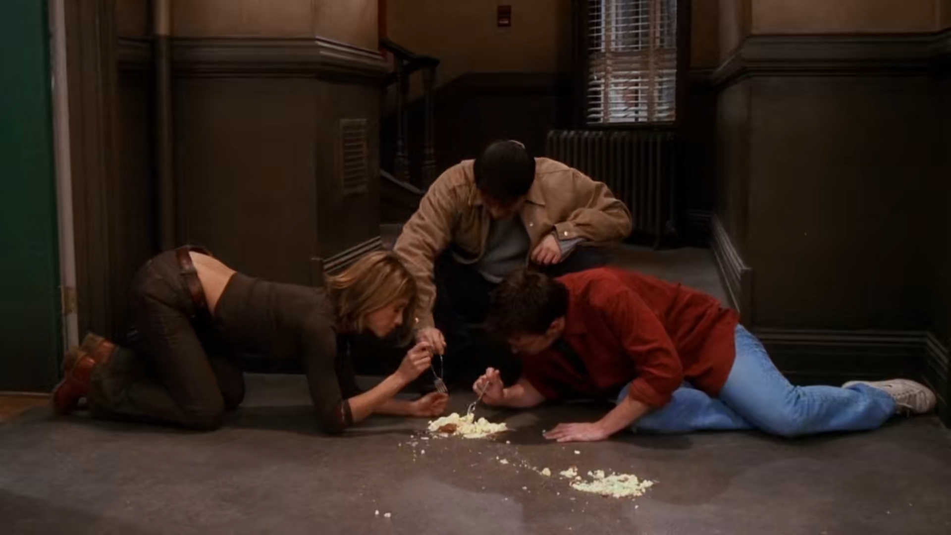 Rachel, Joey y Chandler comiendo un pastel del suelo en Friends.