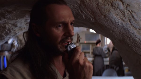 Qui Gon speaking into his communicator.