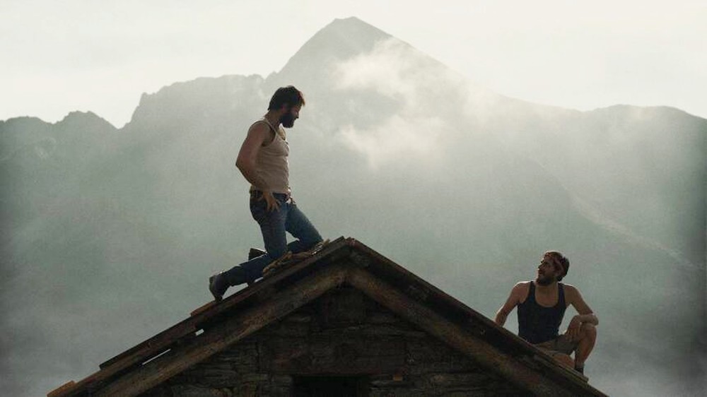 Un hombre mira a otro hombre en una montaña de Las Ocho Montañas.