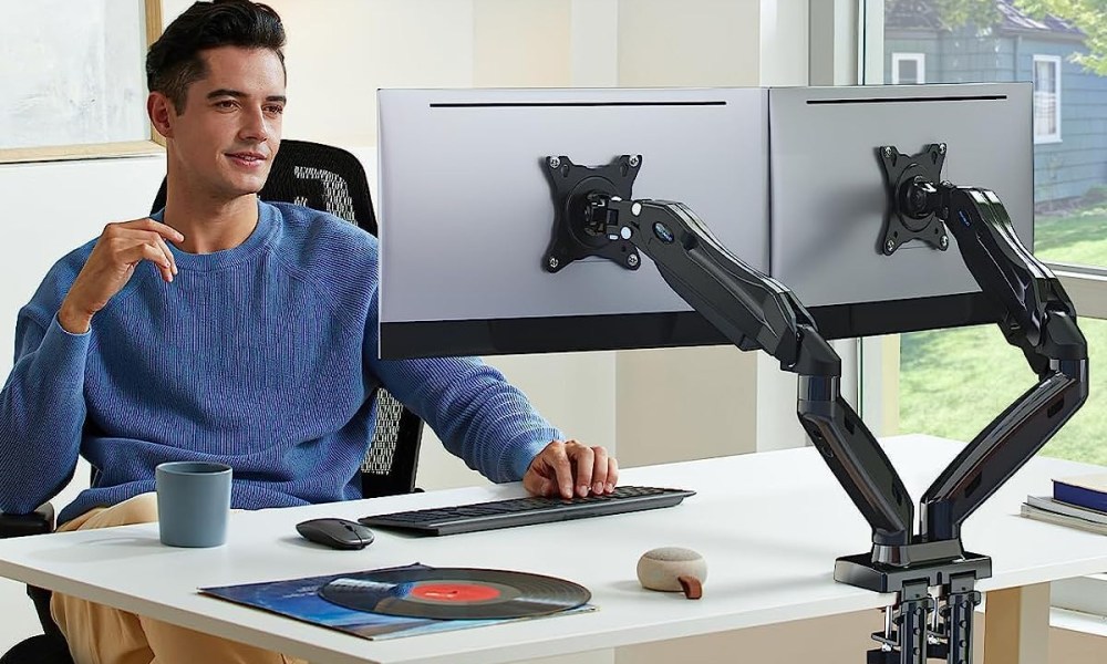 Man using dual monitor arms on his desk.