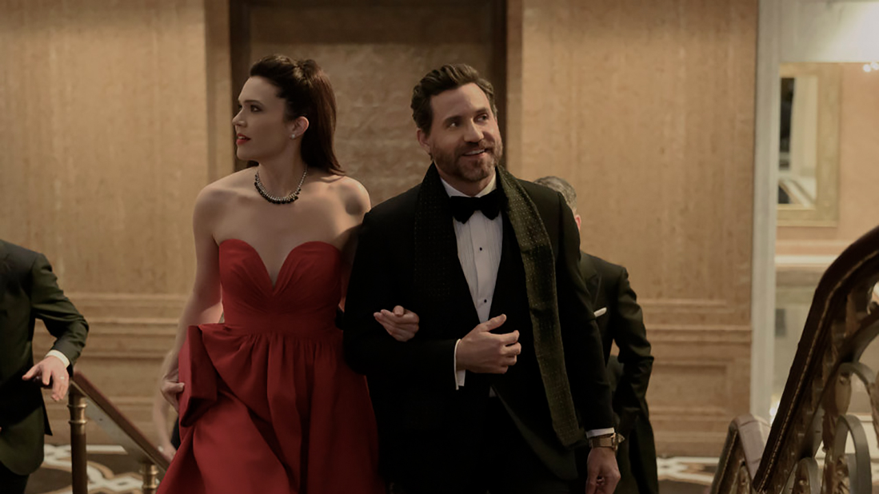 Edgar Ramirez y Mandy Moore como Paulo Macchiarini y Benita Alexander con atuendo formal sonriendo en una escena de la temporada 2 de Dr. Death.