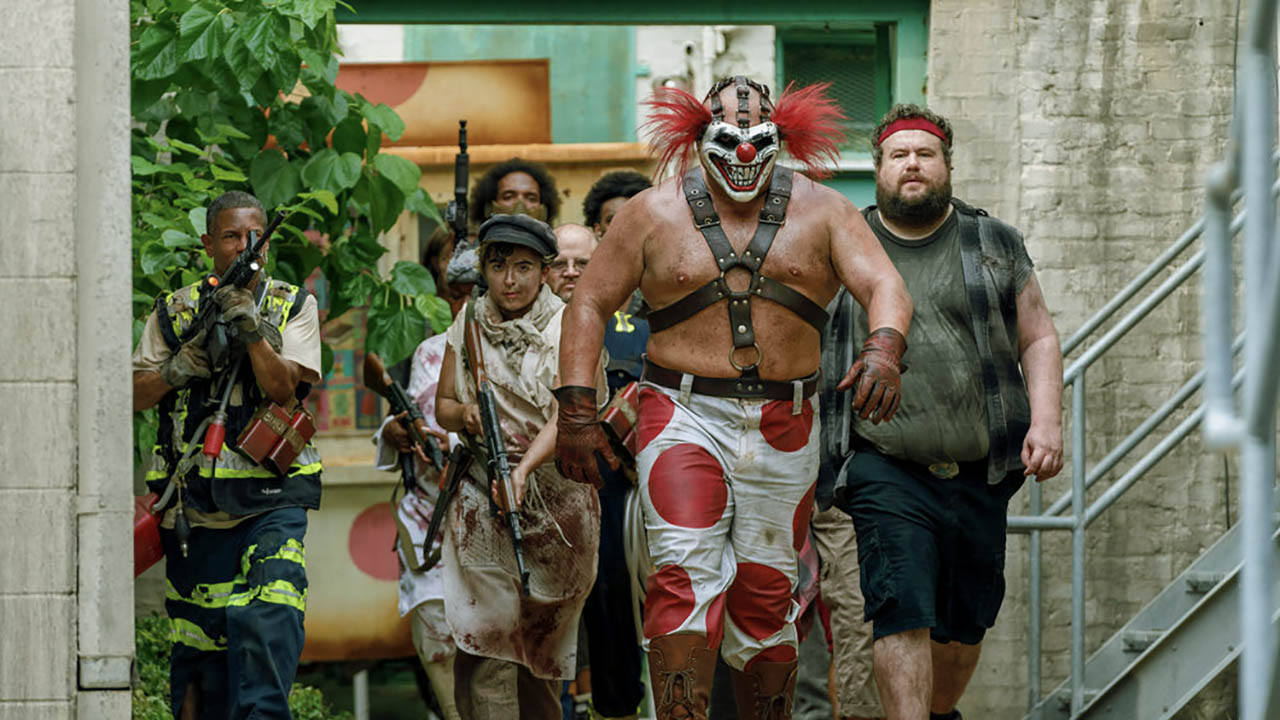 A menacing clown walks with others behind him in a scene from Twisted Metal.