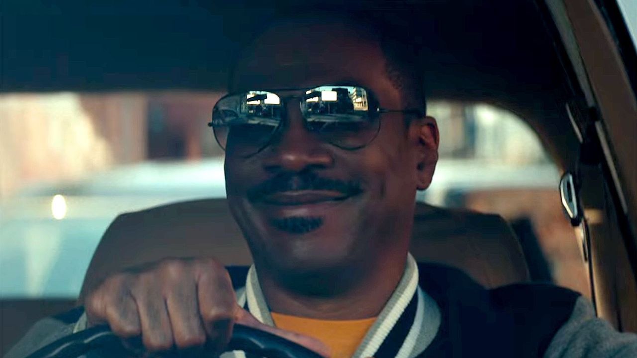 Eddie Murphy as Axel Foley smiling while driving a car in Netflix's "Beverly Hills Cop: Axel F."