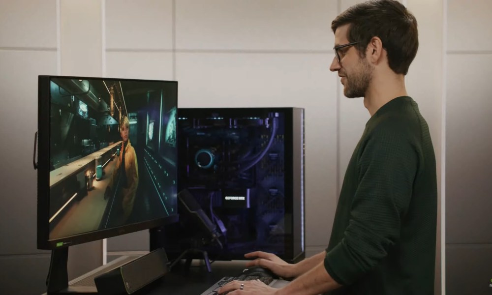 A man stands in front of a gaming PC.