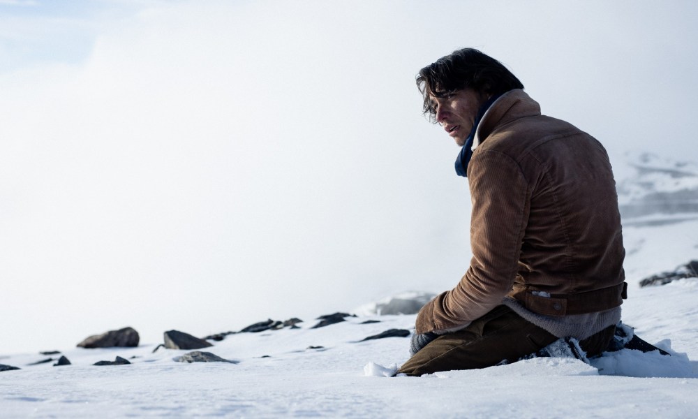 Enzo Vogrincic Roldán sits in the snow in a still from Society of the Snow