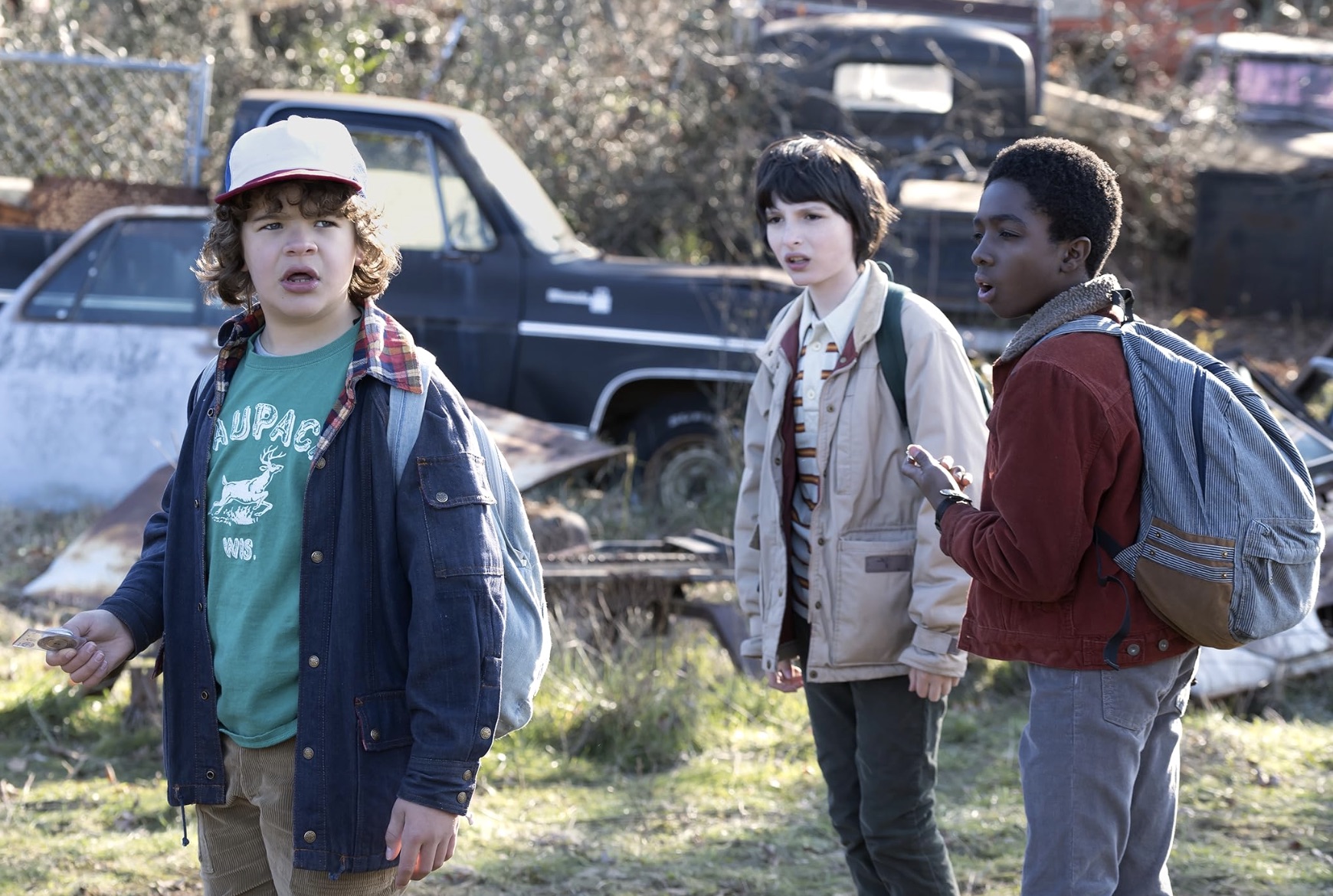 Trois garçons se tiennent côte à côte dans une casse dans Stranger Things.