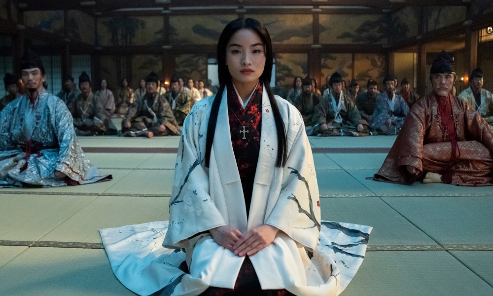 Anna Sawai kneels in a crowded room in Shōgun.