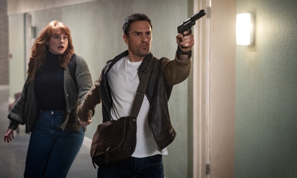 Bryce Dallas Howard stands behind a gun-wielding Sam Rockwell in Argylle.