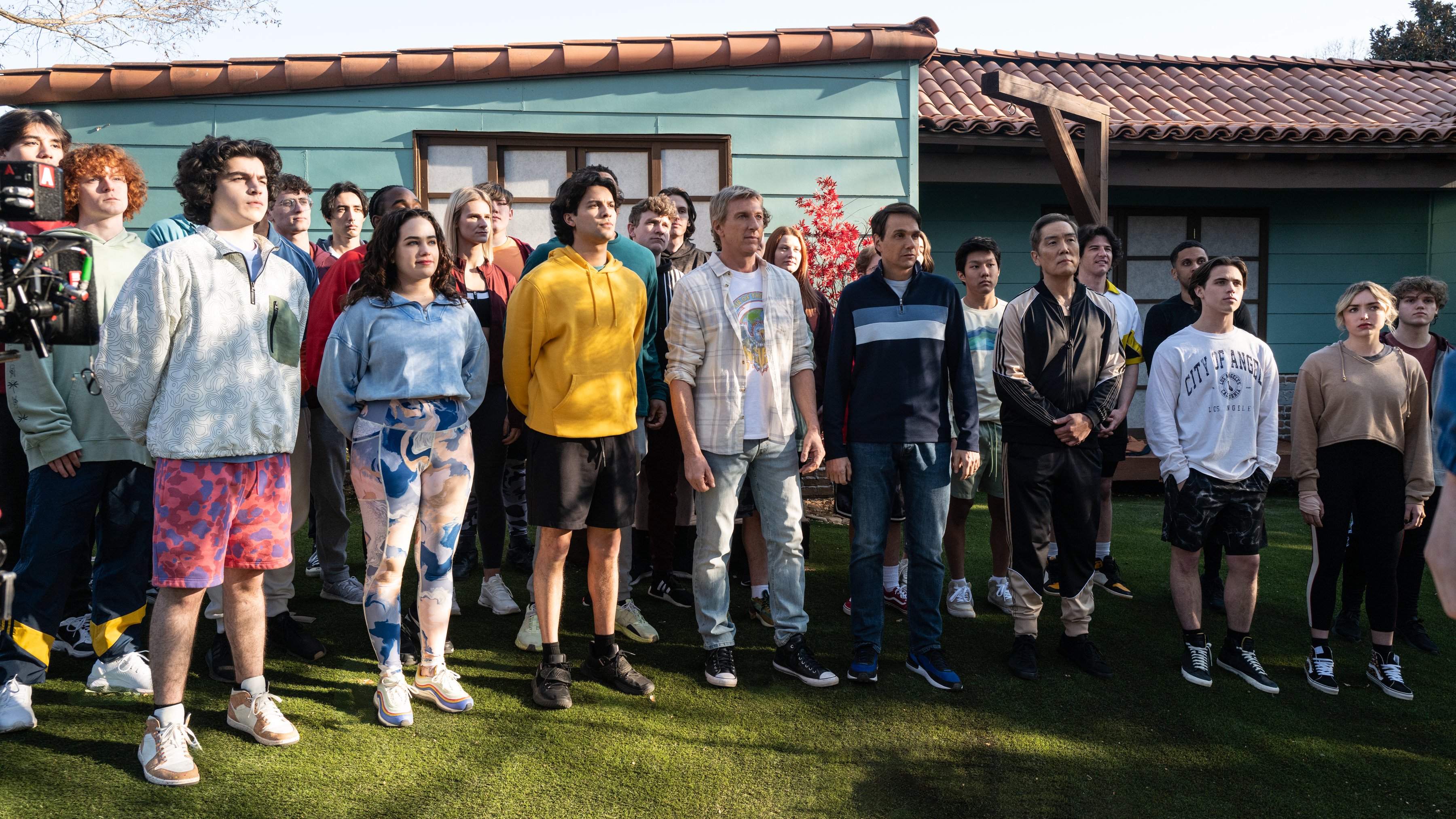 Un grupo de personas están paradas una al lado de la otra frente a una casa.