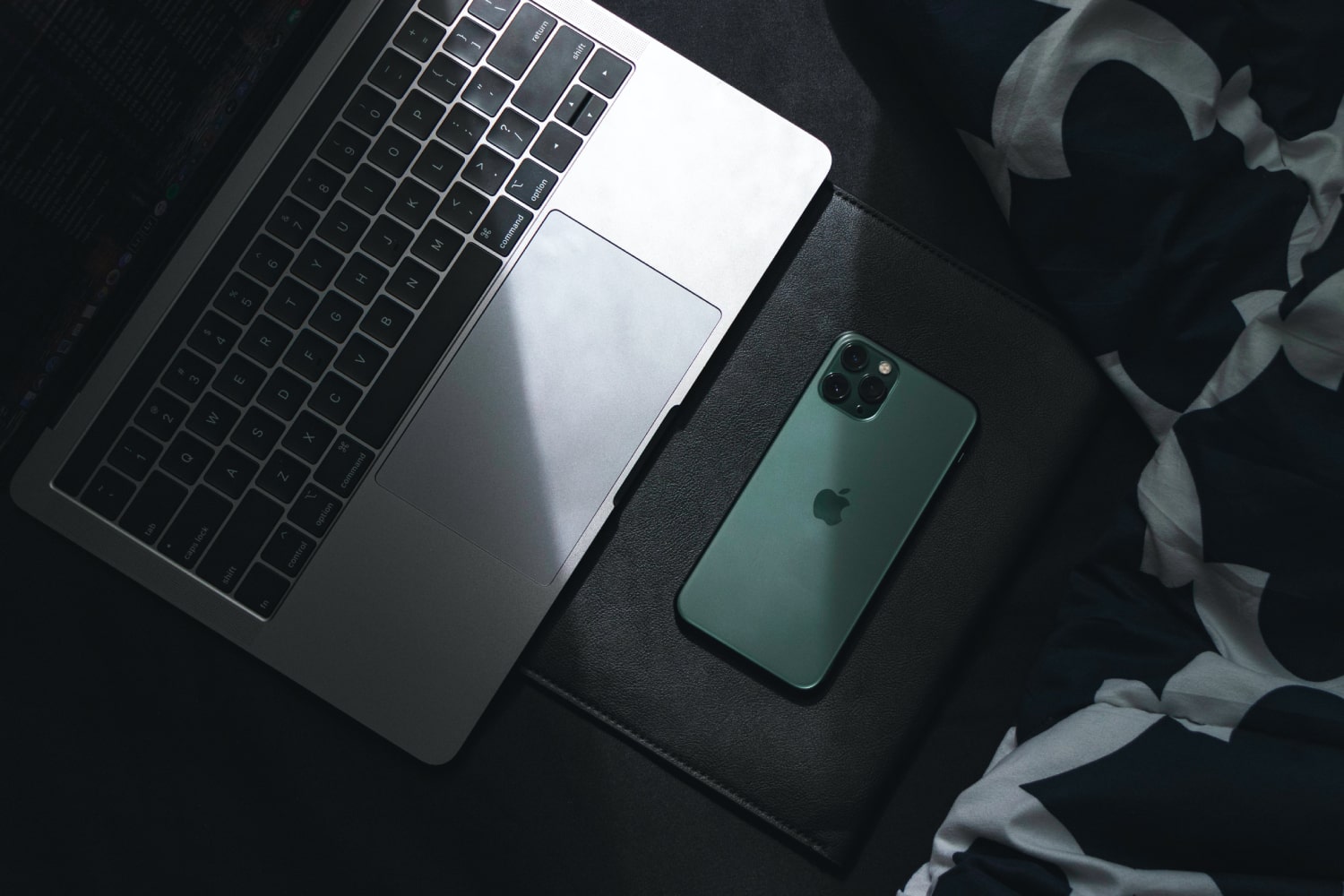 A MacBook and iPhone in shadow on a surface.