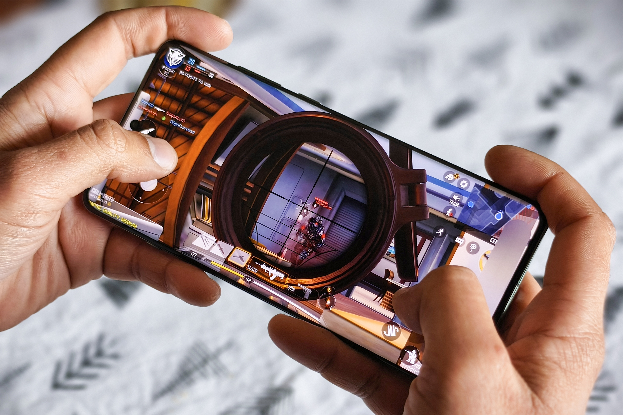 OnePlus 12, который человек держит в руках, запускает Call of Duty Mobile.