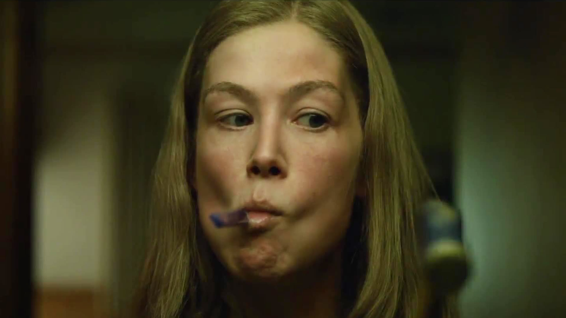 Rosamund Pike dans le rôle d'Amy Elliott Dunne avec une brosse à dents sur la bouche dans le film Gone Girl.