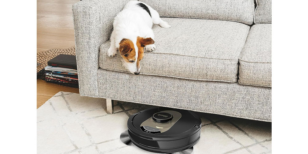 A Shark AI Robot Vacuum moving under a sofa while a dog watches.