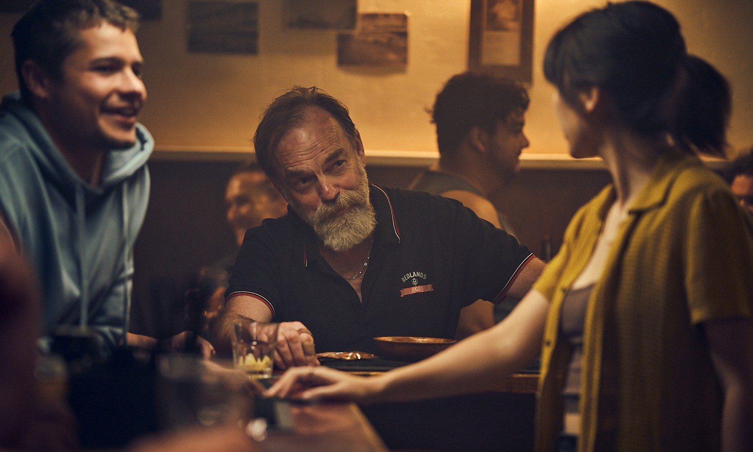 A woman talks to two men in The Royal Hotel.