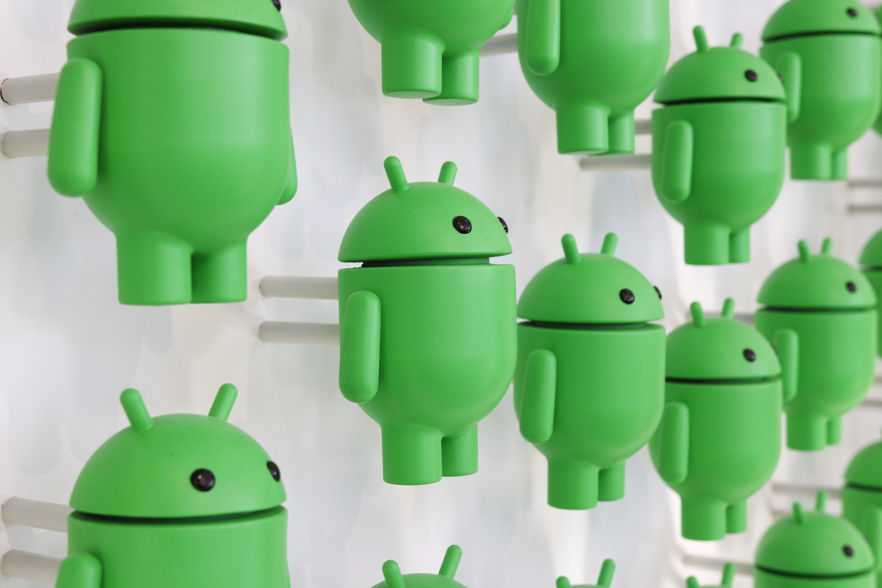 Una foto de muchas figuras de Android en una pared blanca.