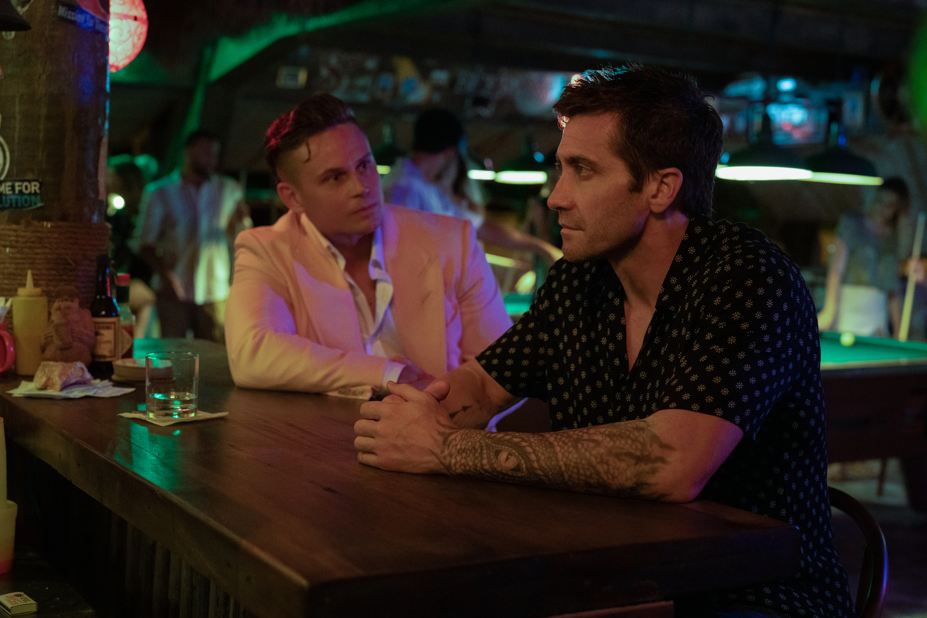 Billy Magnussen está sentado em um bar com Jake Gyllenhaal em Road House.