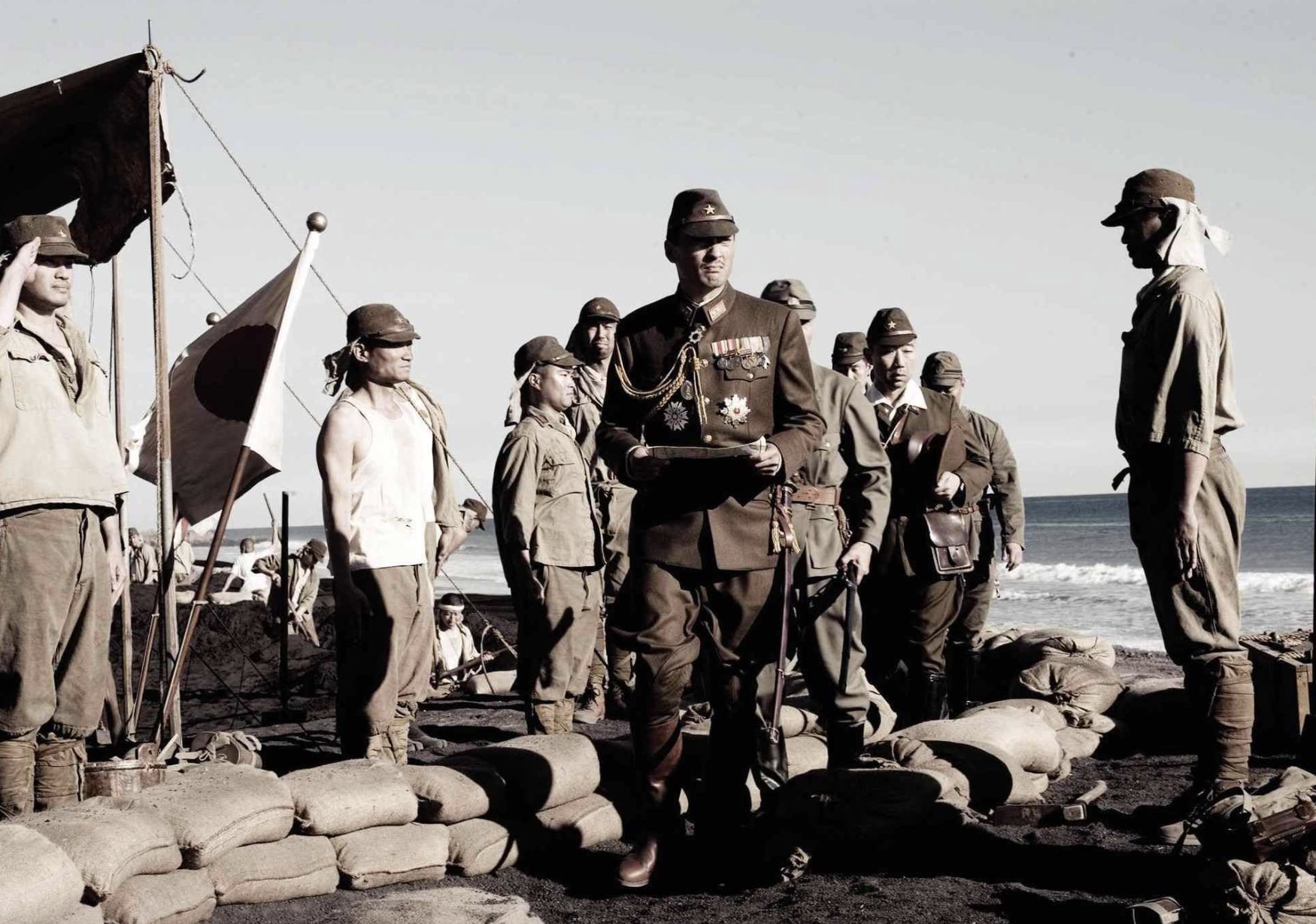 Um grupo de soldados japoneses está na praia enquanto alguém entra em um bunker.