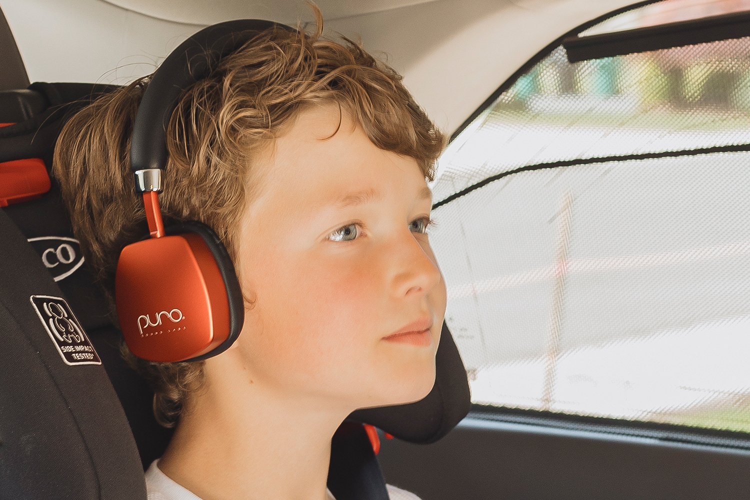 Un enfant portant une paire de casques pour enfants PuroQuiet Plus rouges.