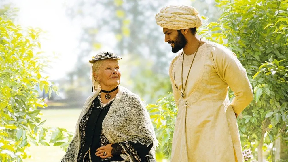 Uma mulher mais velha e um homem se olham em Victoria & Abdul.