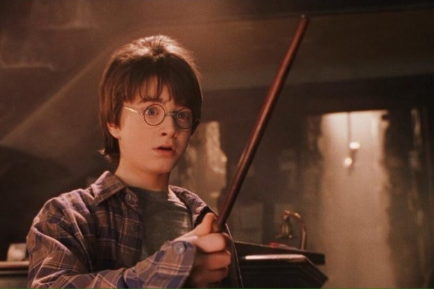 Daniel Radcliffe as Harry wielding his wand with a surprised expression in Harry Potter and the Sorcerer's Stone.