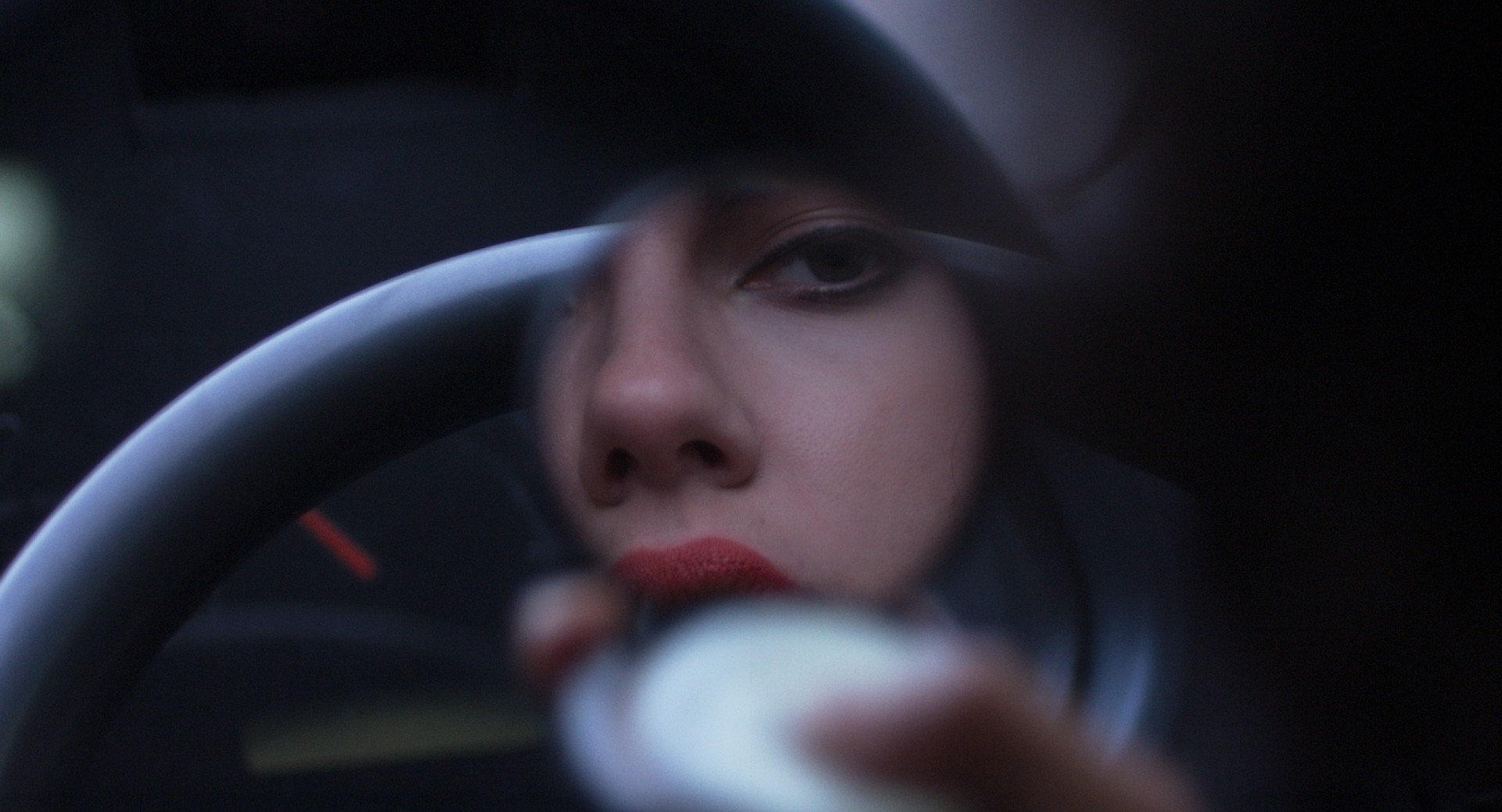 Uma mulher se olha em um espelho compacto em Under the Skin.