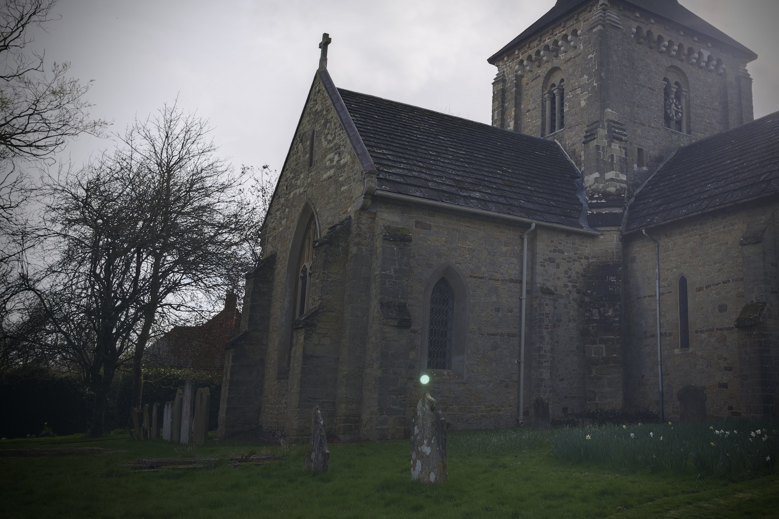 A photo of an orb floating over a gravestone in a churchyard.