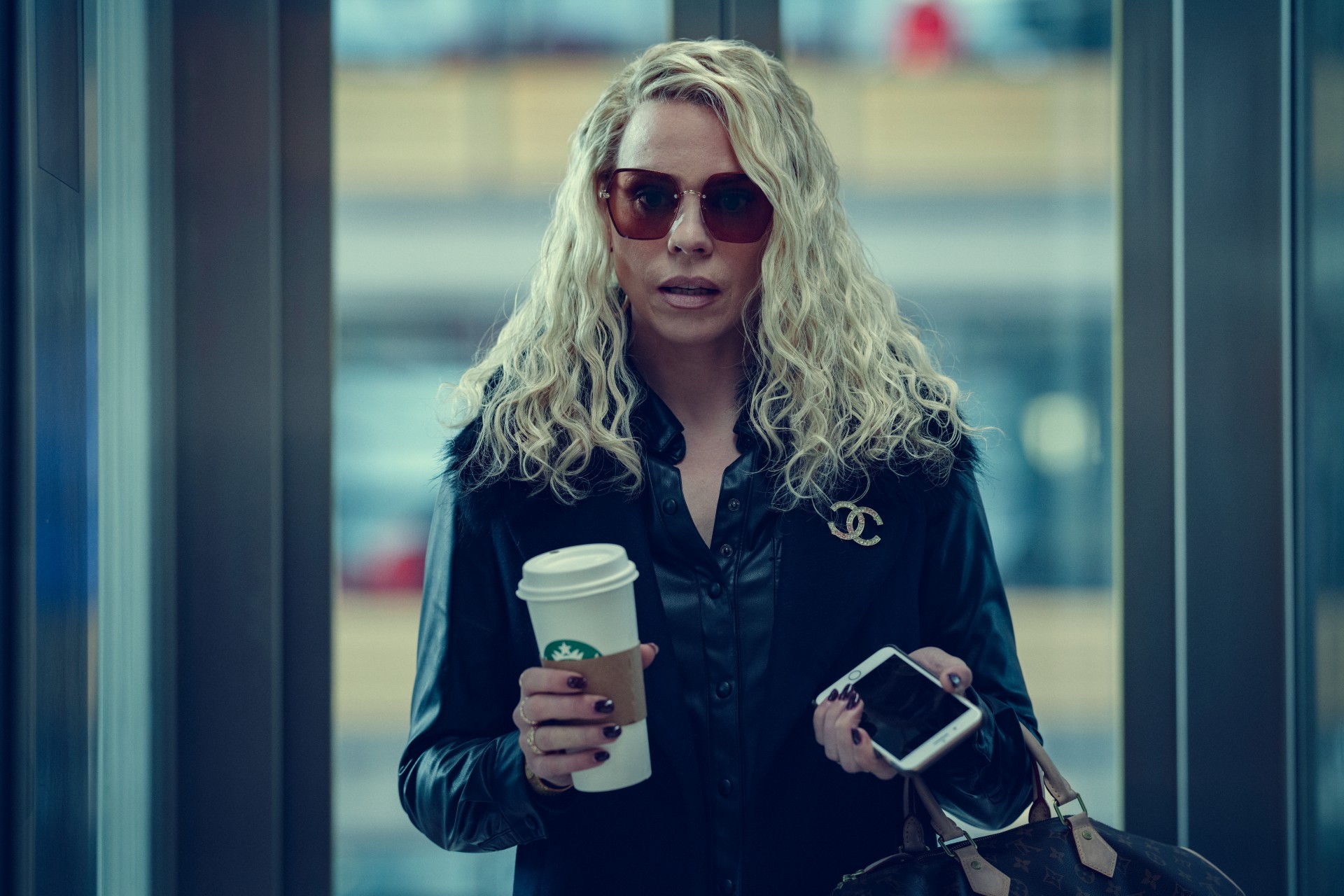 A woman holds a coffee in Scoop.