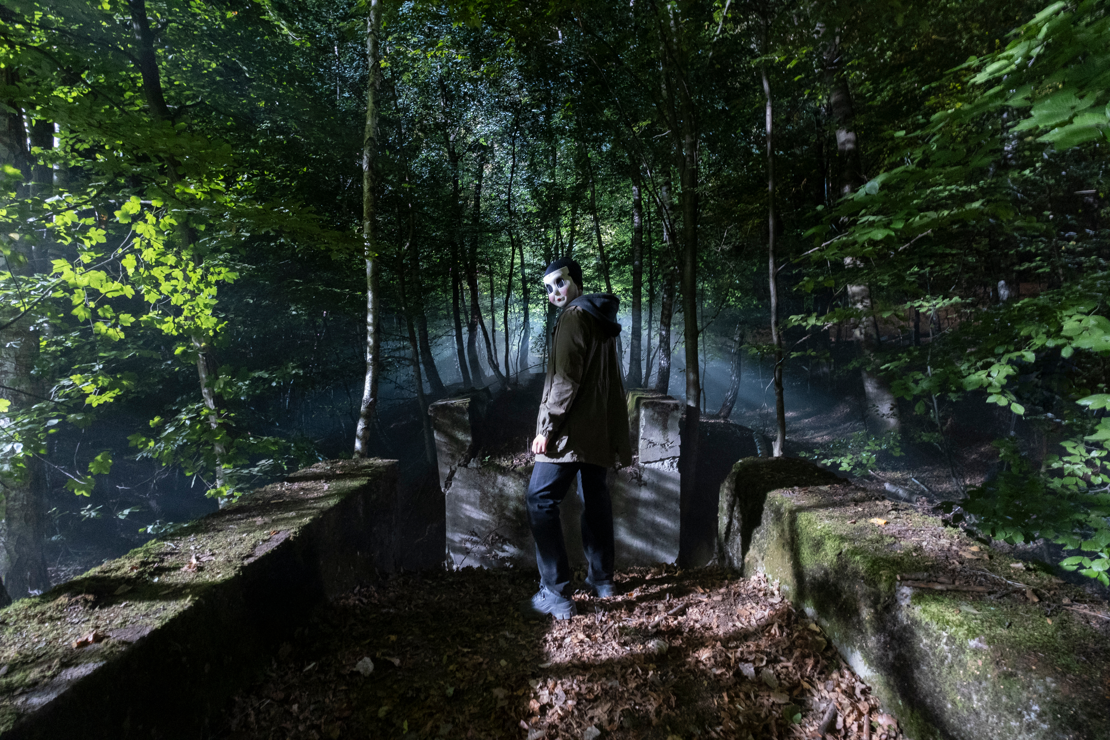 Un tueur masqué se tient dans une forêt dans The Strangers : Chapitre 1.