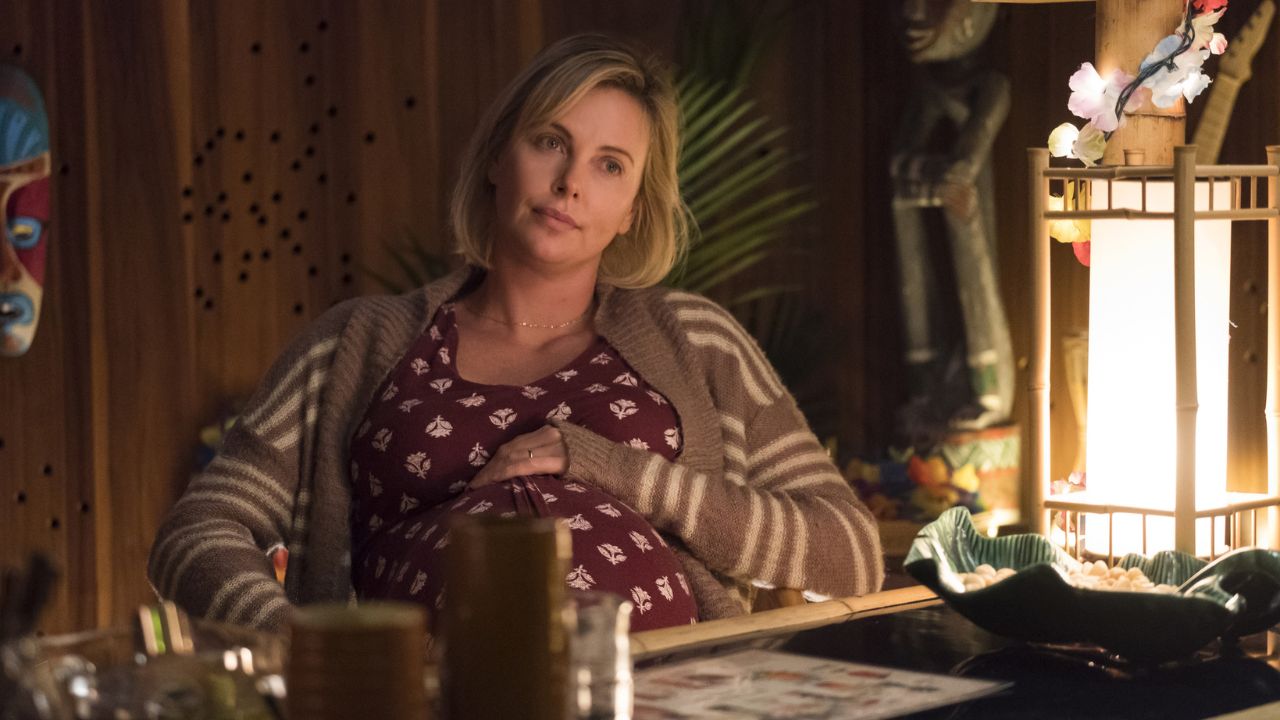 Charlize Theron as a pregnant Marlo sitting on a chair and looking intently at someone off-camera in Tully.