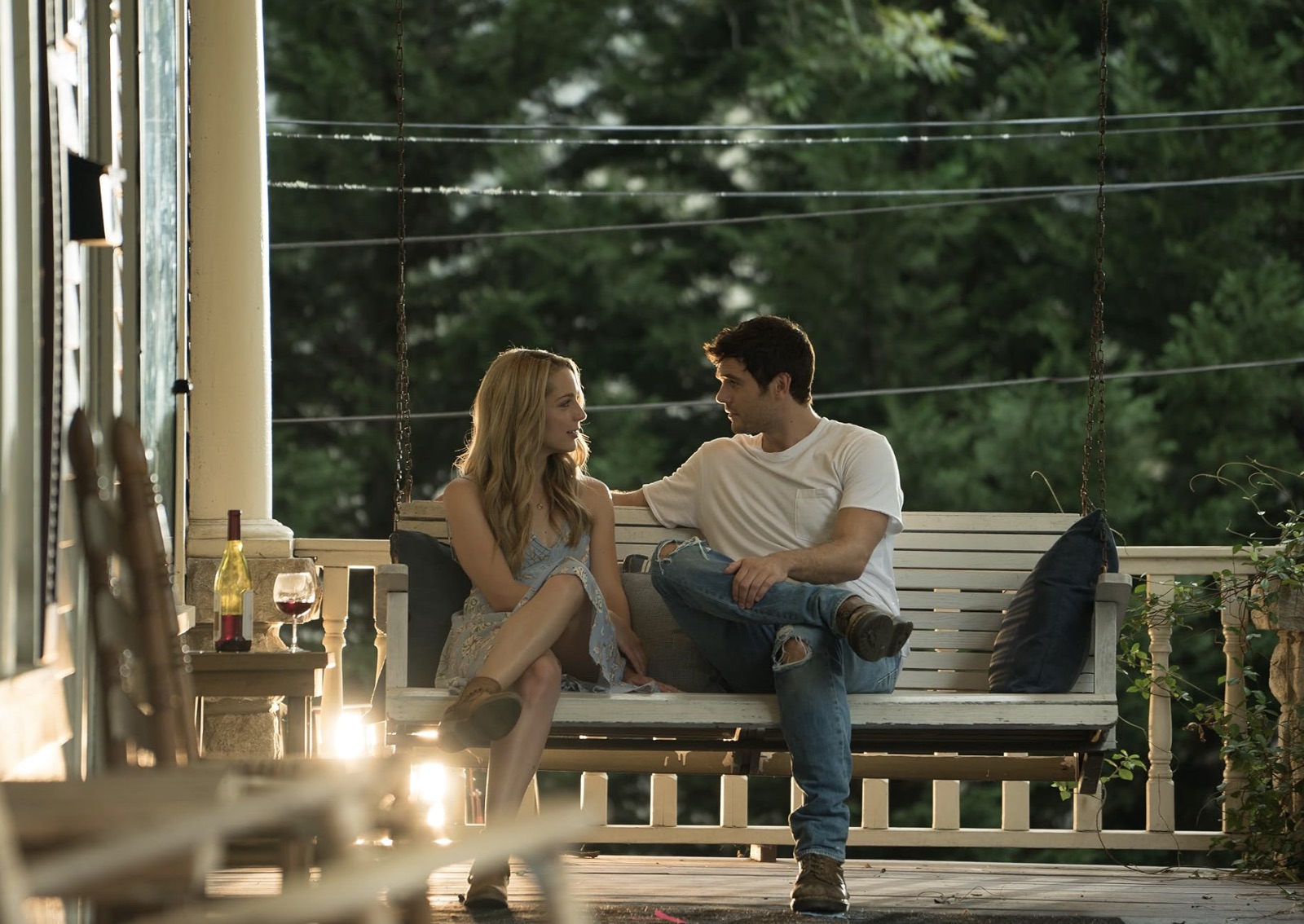 Una mujer joven y un hombre están sentados uno al lado del otro en un porche.
