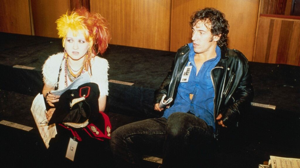 Cyndi Lauper and Bruce Springsteen sit together in The Greatest Night in Pop.