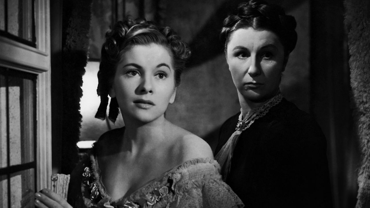 Joan Fontaine as the Second Mrs. de Winter with Judith Anderson as Mrs. Danvers behind her in Rebecca.