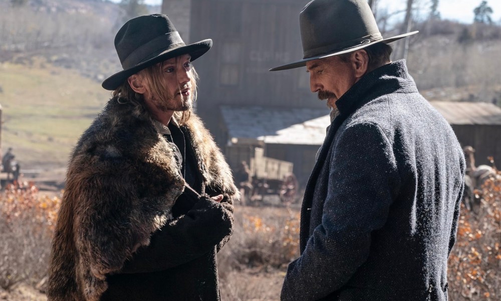 Two men in Cowboy hats stand across from each other and talk.