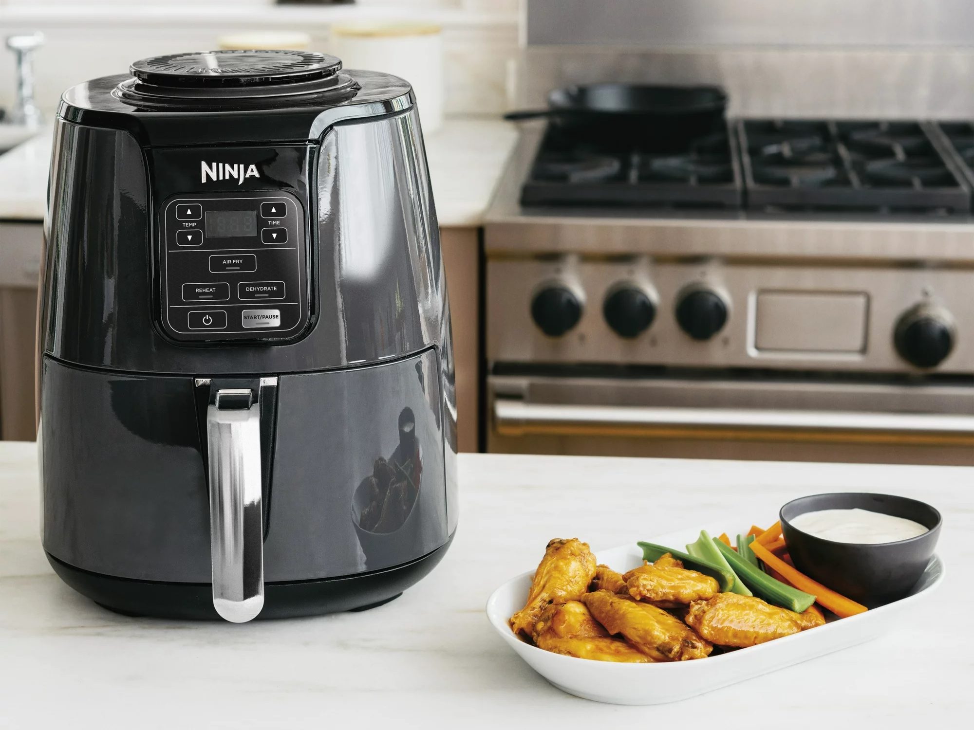 The Ninja 4QT Air Fryer next to a plate of food.