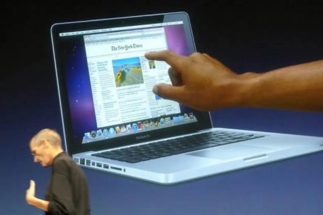 Steve Jobs frente a un gráfico de un MacBook con pantalla táctil.