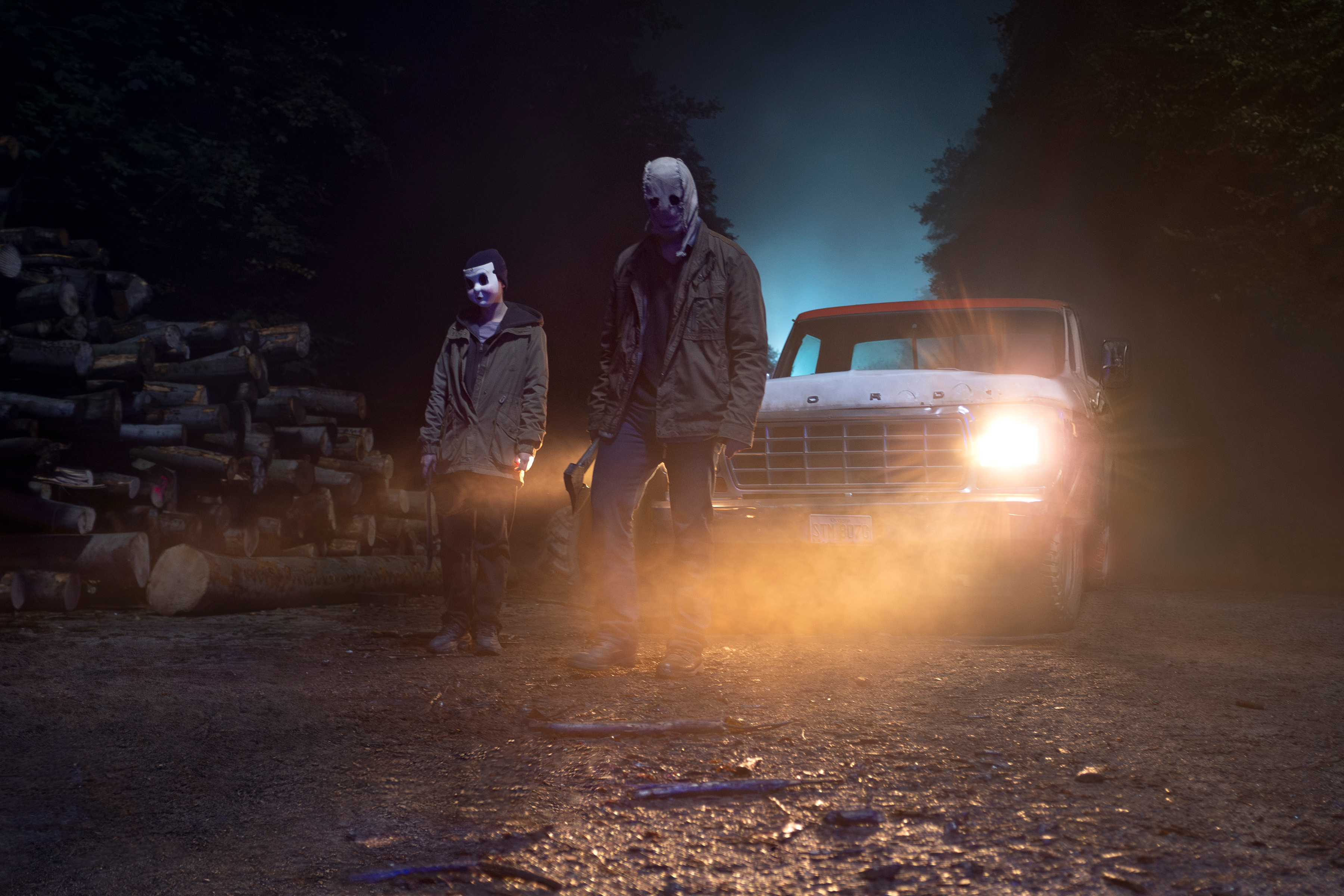 Deux tueurs masqués se tiennent près d'un camion dans The Strangers : Chapitre 1.