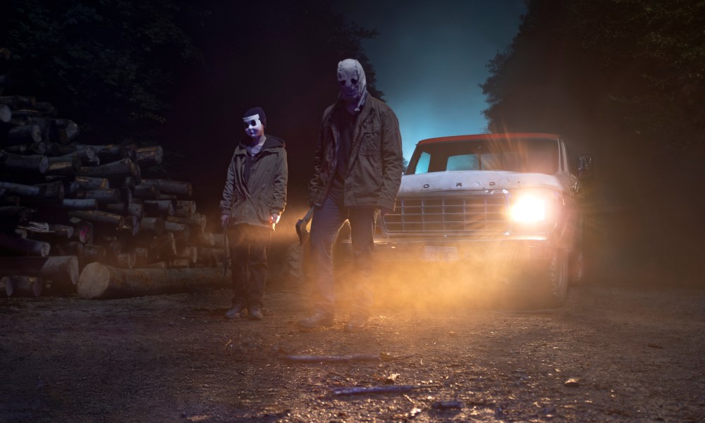 Two masked killers stand near a truck in The Strangers: Chapter 1.