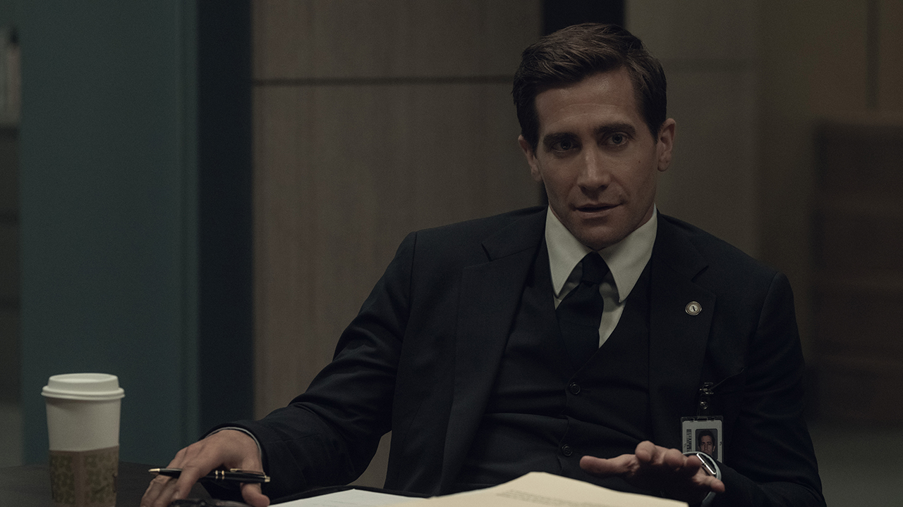 Jake Gyllenhaal sitting behind a desk wearing a suit in a scene from the show Presumed Innocent on Apple TV+.