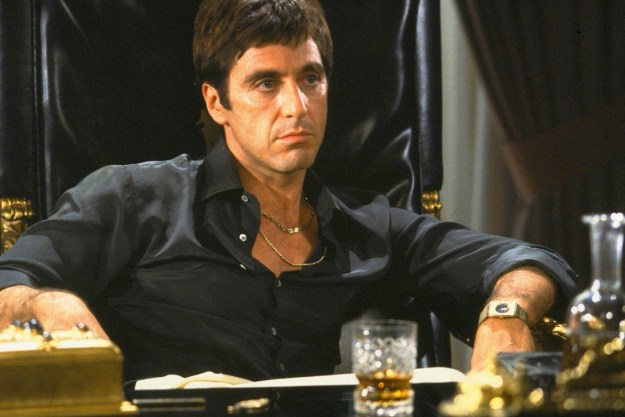 Al Pacino as Tony Montana in Scarface sitting at his desk in an iconic scene.