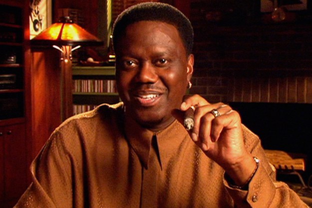 Bernie Mac smiling and holding up a cigar while talking to the camera on The Bernie Mac Show.