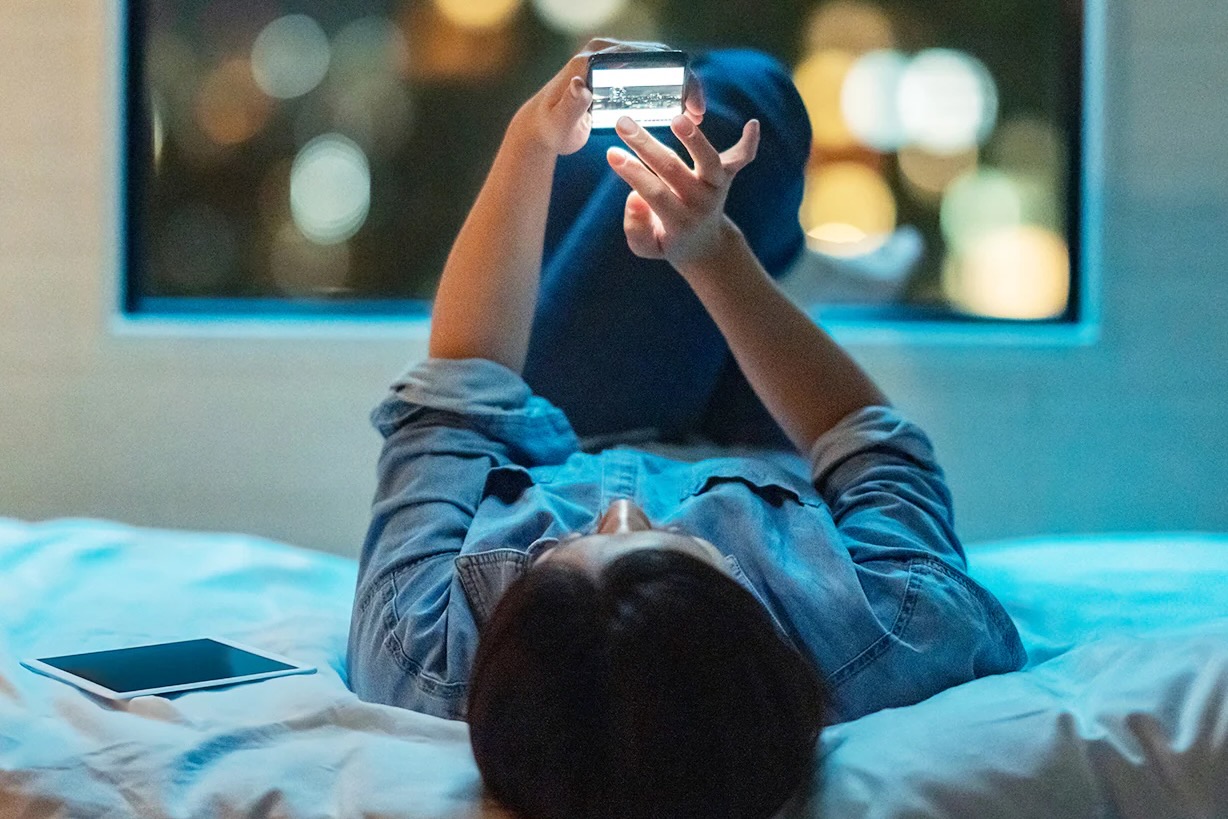 Person holding a phone while laying on a bed.