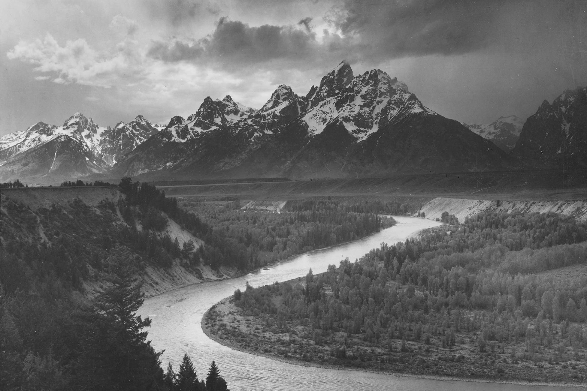 Ansel Adams' panorama of Grand Teton National Park with the peak in the background and a meandering river in the forest.