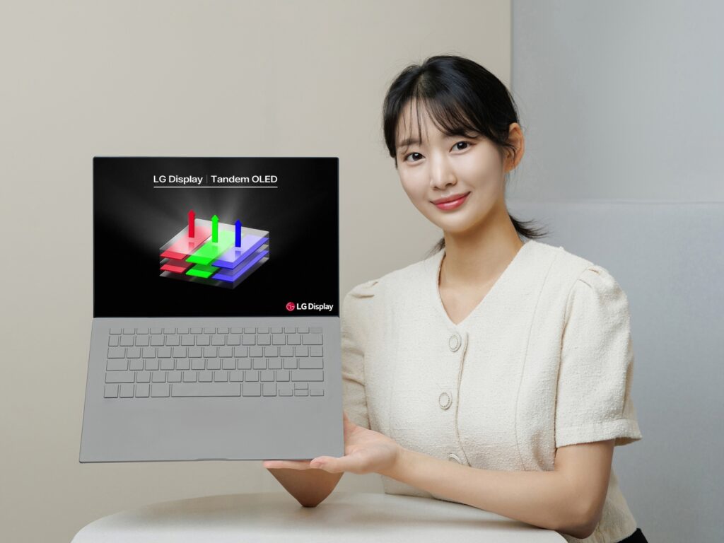 Une femme tient un ordinateur portable portant le logo LG Tandem OLED.