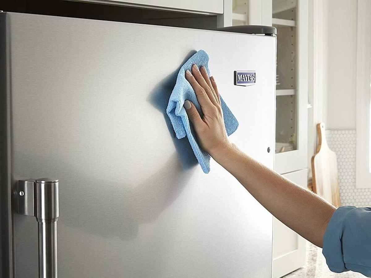 Close-up of a handing wiping down the freezer door of the Maytag 21.2 cu. ft. refrigerator.