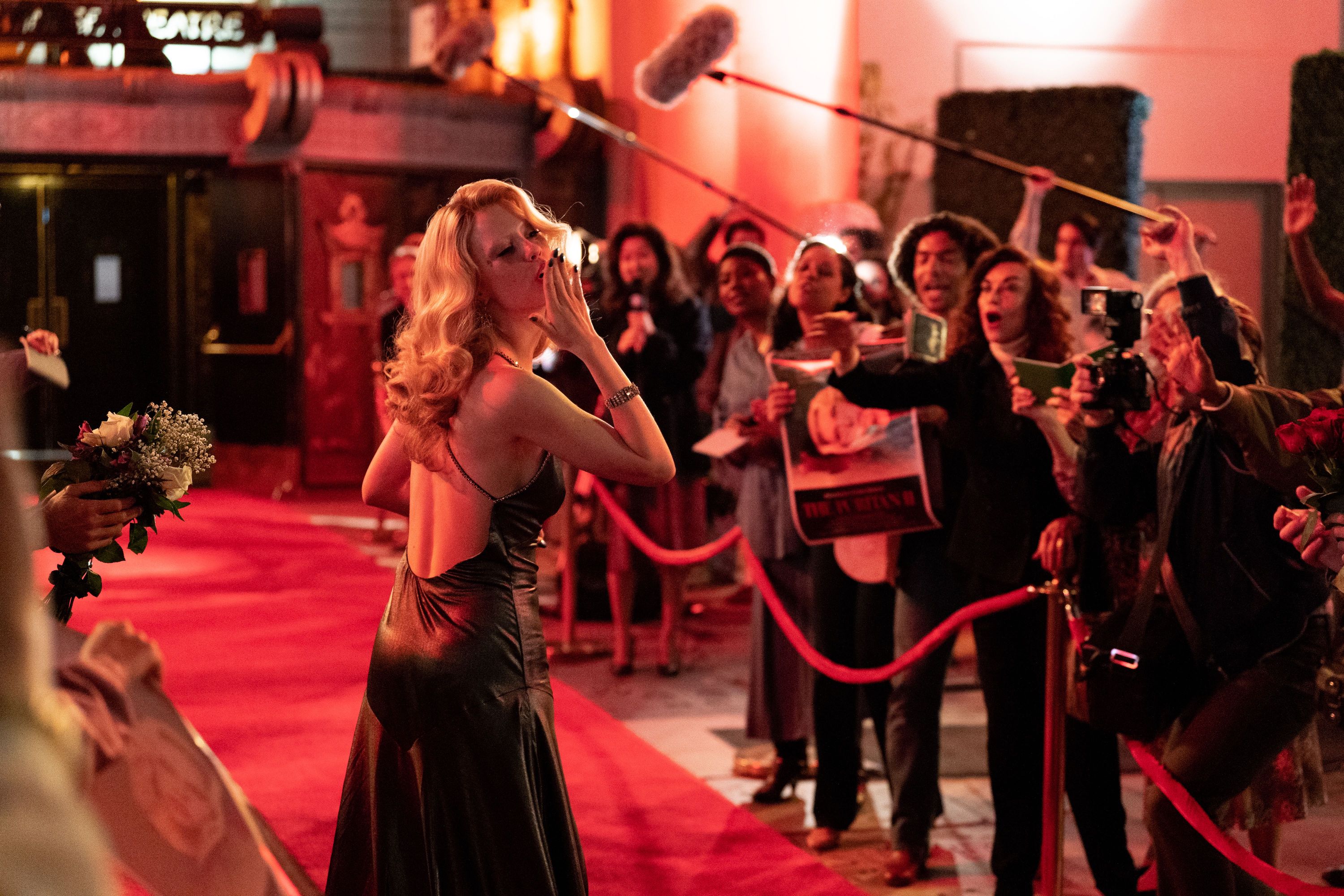 Une femme marche sur le tapis rouge et envoie un baiser.