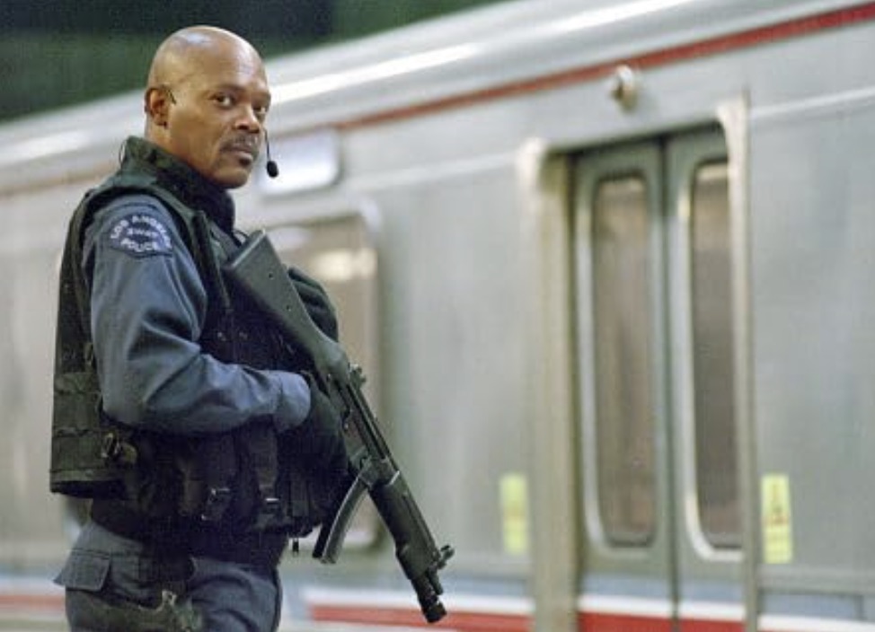 Samuel L. Jackson holds a gun outside of a subway.