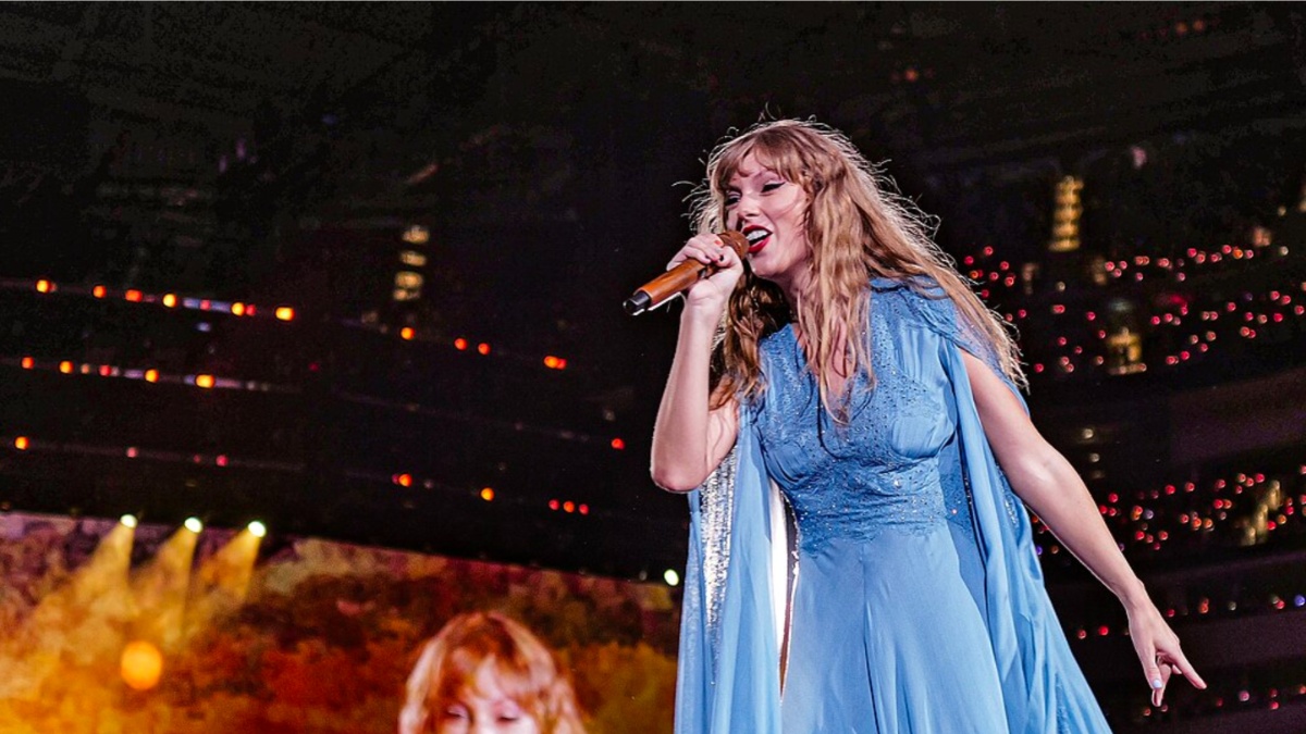 Taylor Swift sostiene un micrófono y canta.